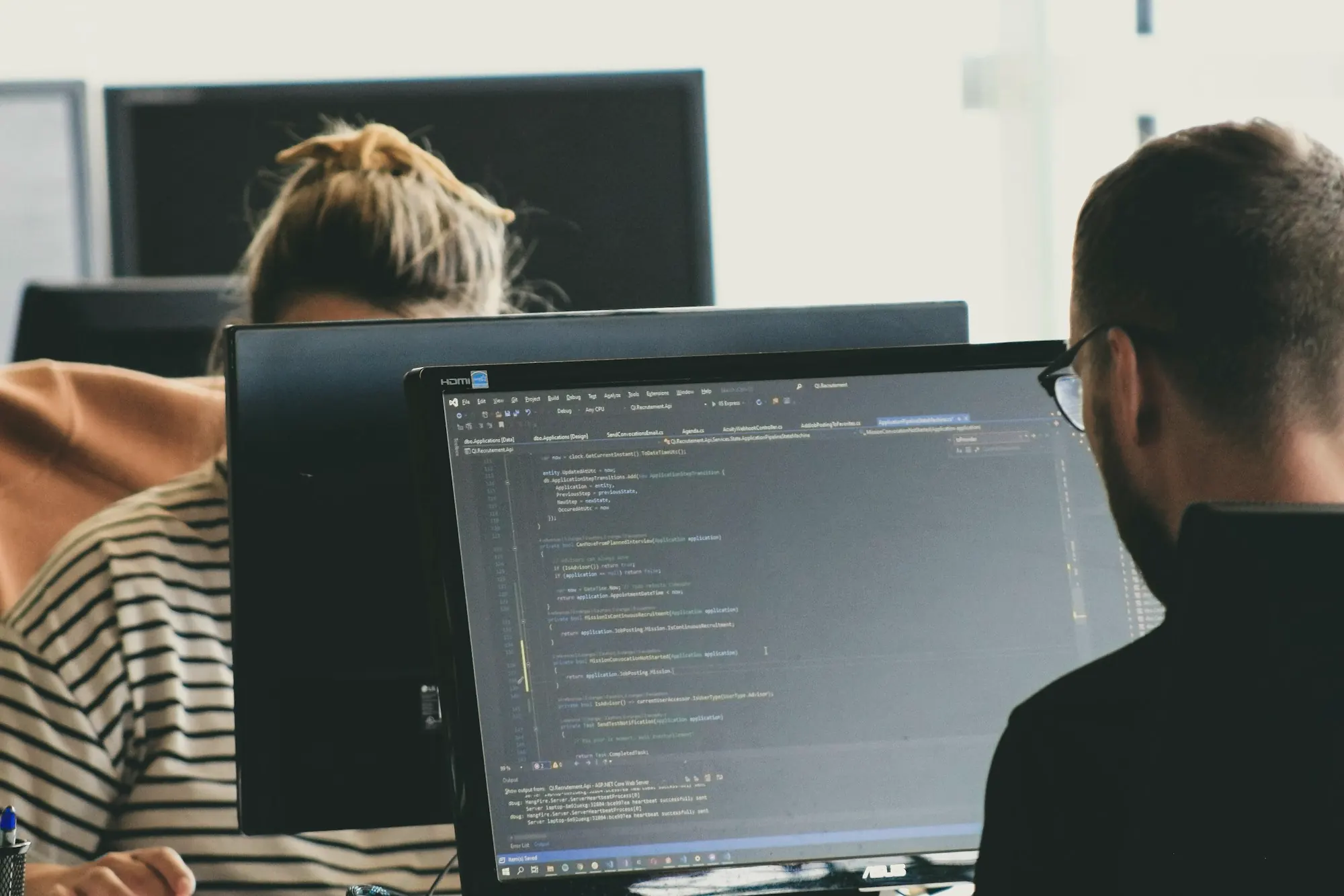 Two developers working on code at their monitors